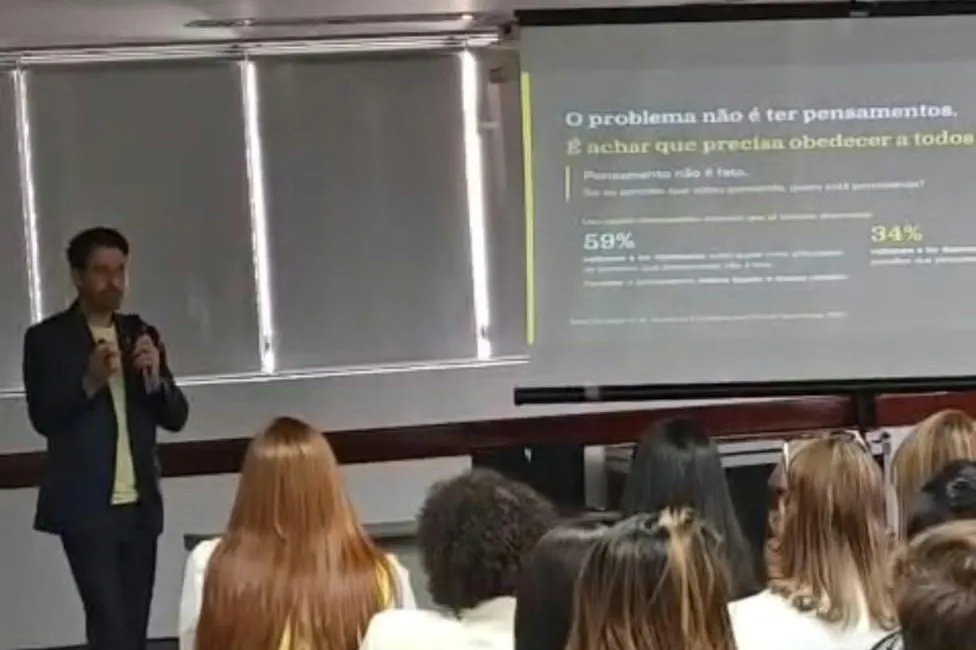 Rafael Macedo falando para uma plateia de colaboradores, com a apresentação projetada ao fundo